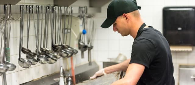 Работник на мойку контейнеров на производстве суши